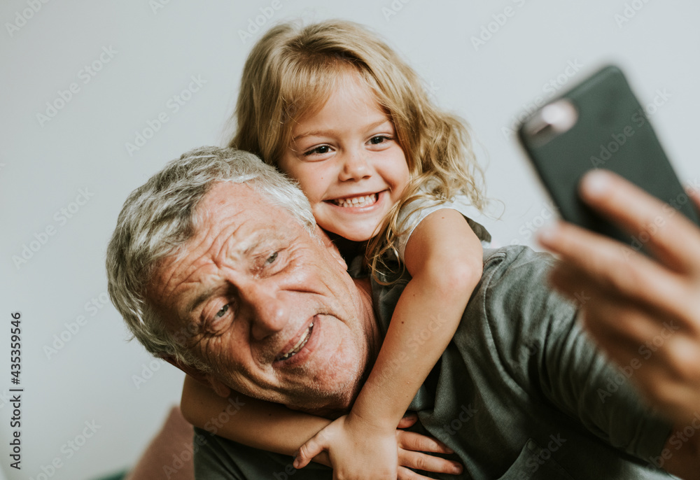Grandfather taking a selfie with his granddaughter - obrazy, fototapety, plakaty 