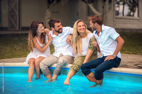 Group of young people sitting on the swimming pool.
