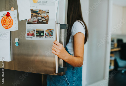 Vászonkép Girl picking something to eat out of the fridge