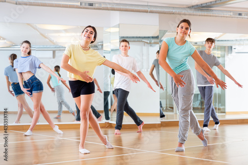 Fototapeta Naklejka Na Ścianę i Meble -  Diligent friendly smiling teenagers learn dance movements in dance class