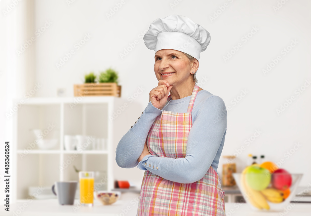 cooking, culinary and old people concept - portrait of smiling senior woman or chef in toque in apron thinking over home kitchen background cooking, culinary and old people concept - portrait of smiling senior woman or chef in toque in apron thinking over home kitchen background