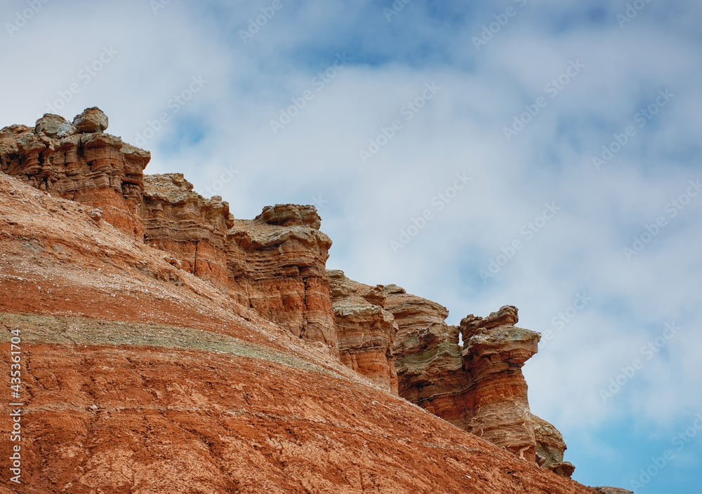 The walls of the canyon among the ancient desert steppe fields against the background of the blue sky, geological deposits of different times, clay, erosion. Rocky cliffs, hills and mountains in the A