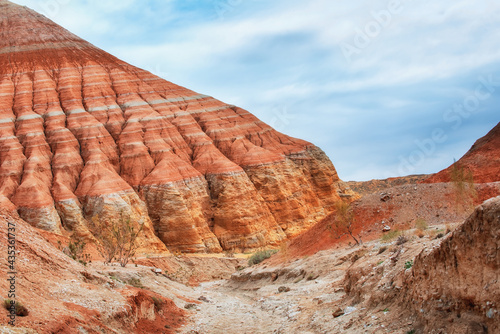 The hills and mountains of ancient sediments with patterns of erosion, red yellow and white clay and desert vegetation. View of the Altyn-Emel park in Kazakhstan