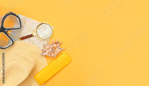 Swimming mask, hat, map, magnifier, sunblock and shell on a yellow background. The concept of choosing a place for rest, vacation at sea, active rest. Place for your text, design. top view, copy space