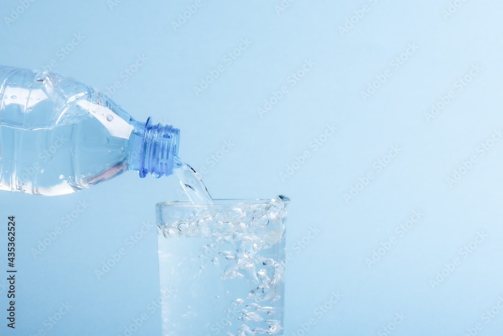 Pouring water from a plastic bottle into a glass beaker. Pouring water from a plastic bottle into a glass beaker.