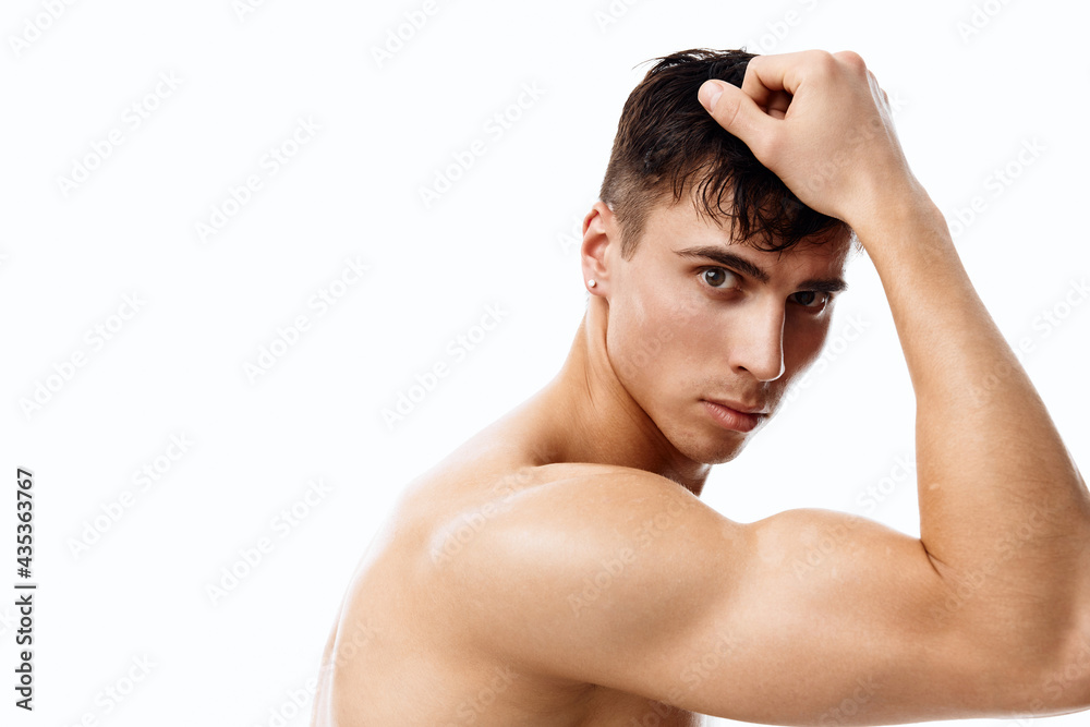 Fototapeta premium confident man athlete with a pumped-up torso touches his head with his hand