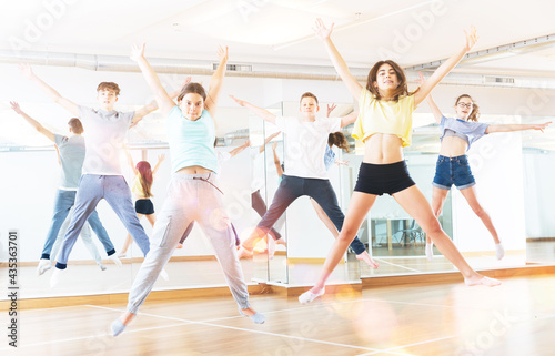 Satisfied teenage boys and girls jumping having fun during dance class