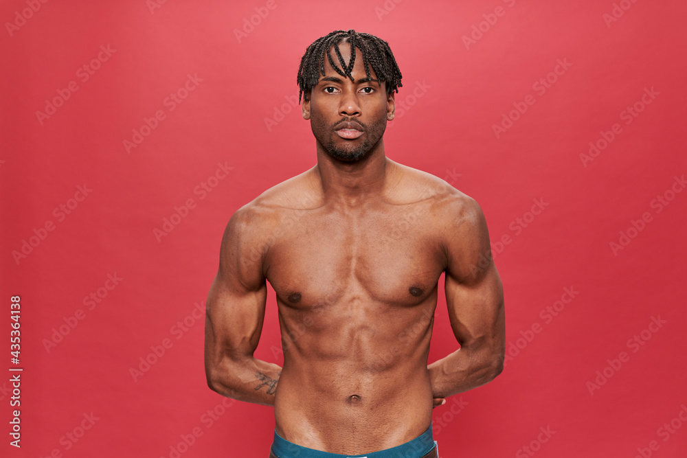 Fototapeta premium Shirtless muscular black man looking at camera on red background