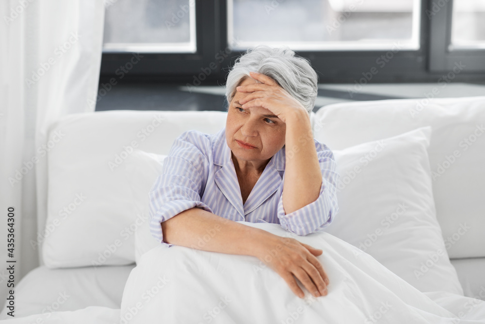 health, old age and people concept - senior woman in pajamas suffering from headache sitting in bed at home bedroom health, old age and people concept - senior woman in pajamas suffering from headache sitting in bed at home bedroom