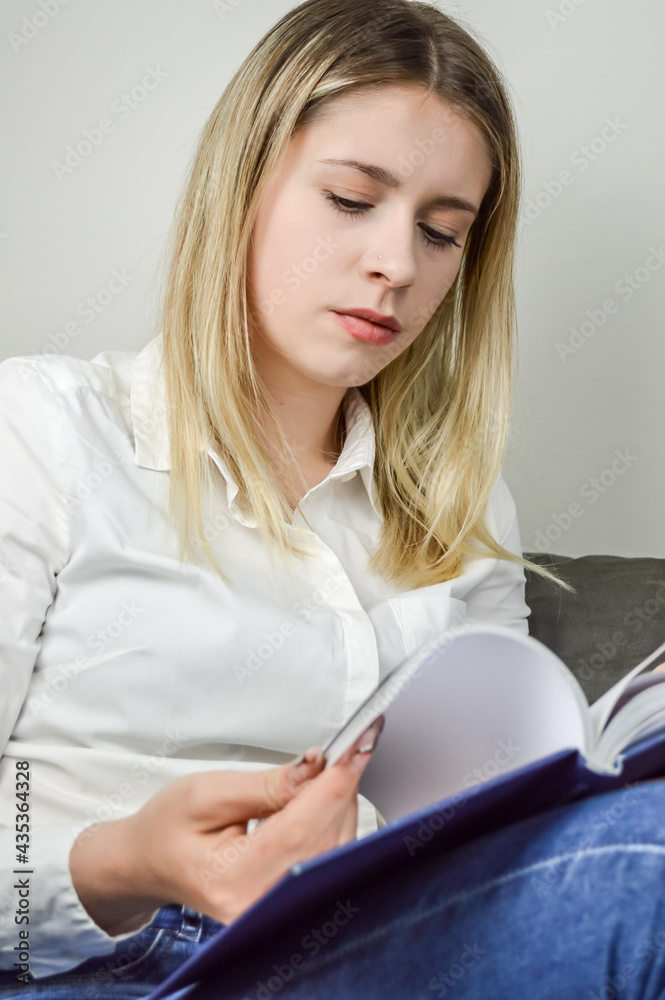 Young blonde long haired woman concentrated in reading a book relaxing Young blonde long haired woman concentrated in reading a book relaxing