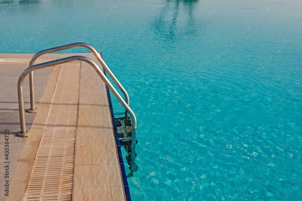 Ladder in swimming pool with turquoise water