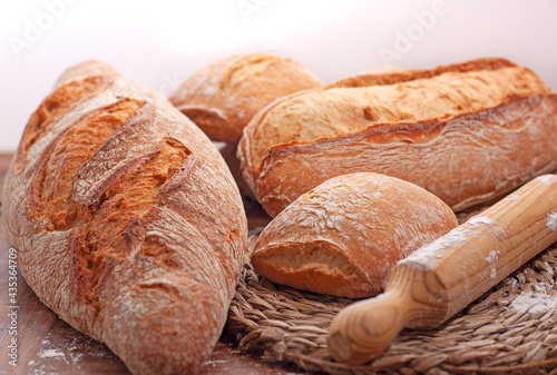  Concepto de unos panes con un mantel de esparto con un rodillo de madera para hacer el pan con un fondo blanco en la parte superior.