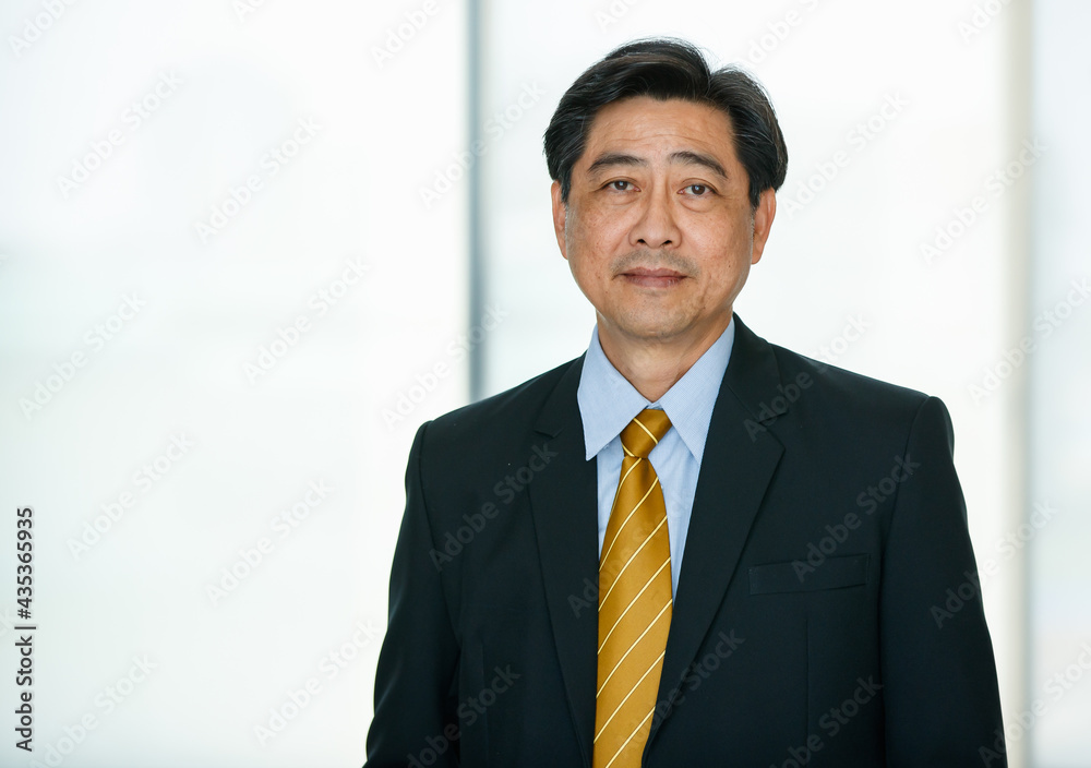 50s aged Asian senior executive businessman wearing formal suit with luxury necktie, standing in indoor office, looking at camera, smiling with satisfaction, confidence 50s aged Asian senior executive businessman wearing formal suit with luxury necktie, standing in indoor office, looking at camera, smiling with satisfaction, confidence