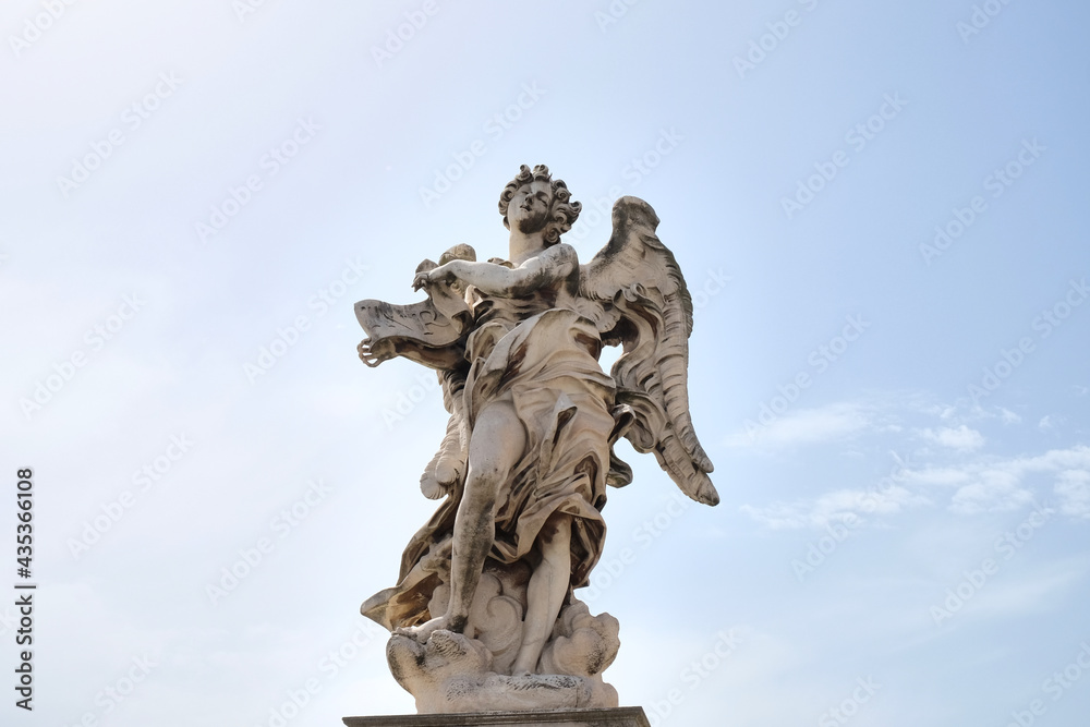 Angel with the inscription holding it in his hands with the sky in the background on the Sant Angelo bridge Rome, Italy.