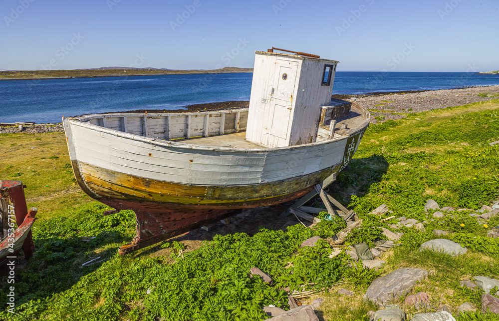 Old and dilapidated wooden fishing boat on the shore at Vardö, Finnmark, Norway