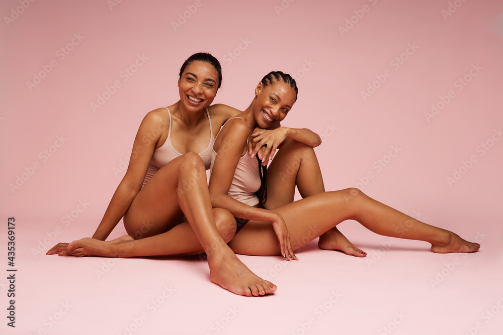 Mixed race women wearing under garments sitting together Mixed race women wearing under garments sitting together