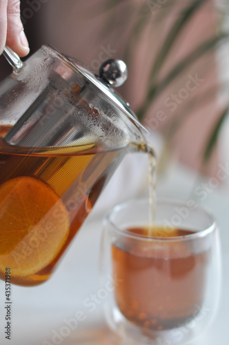 Tea pot male hand morning concept - transparent teapot in a man's hand on white backgrouhd morning routine man's care healthy lifestyle a man pours tea from a transparent teapot into a cup photo