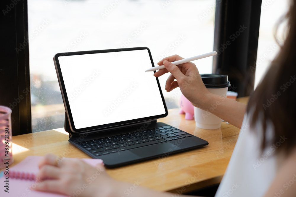 Mockup image of a woman hand using stylus with a black tablet with white blank screen on wooden desk. Mockup image of a woman hand using stylus with a black tablet with white blank screen on wooden desk.