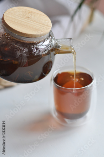 Tea pot male hand morning concept - transparent teapot in a man's hand on white backgrouhd morning routine man's care healthy lifestyle a man pours tea from a transparent teapot into a cup photo