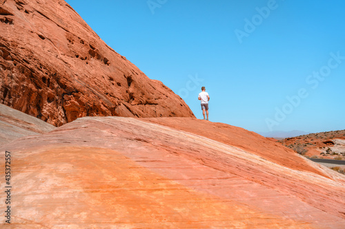 Canvas Print A young man stands on a high rock in the Valley of Fire National Park, Nevada