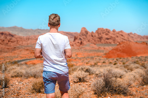 A young man enjoys a beautiful desert landscape in the Valley of Fire National Park, Nevada © KseniaJoyg