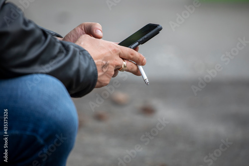 smoking a cigarette and writing a message, outside, horizontal