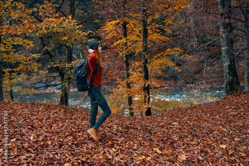 a traveler with a backpack walks in the park in nature near the river in autumn