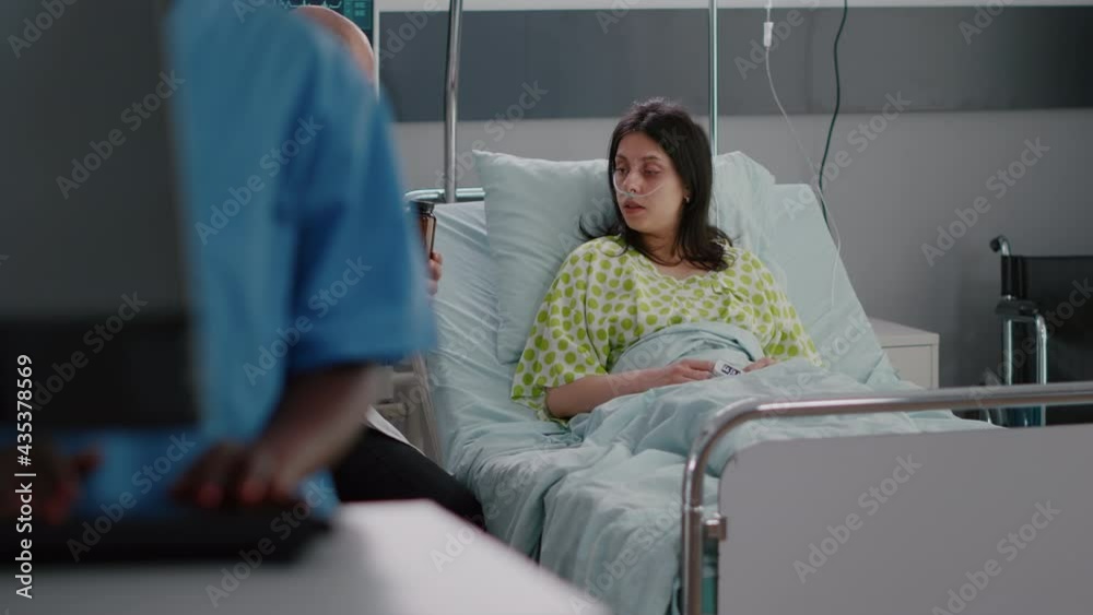 Physician medic examining sick woman patient during pharmaceutical appointment in hospital ward. Doctor discussing medication treatment explaining pill prescription while patient sitting in bed Physician medic examining sick woman patient during pharmaceutical appointment in hospital ward. Doctor discussing medication treatment explaining pill prescription while patient sitting in bed