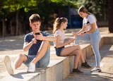 Teenager is passionate about playing on a smartphone on a city street