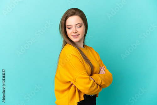 Teenager girl over isolated blue background with arms crossed and happy