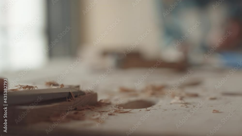 Macro of unrecognizable female joiner carving piece of timber with chisel in workshop