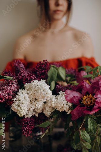 colorful multicolored bouquet of flowers and a girl on the background. white and purple lilac. bloom and beautiful girl out of focus.