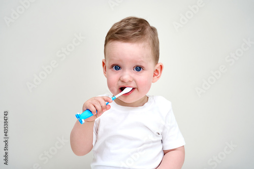 a small child with blue eyes holds toothbrushes in his hands