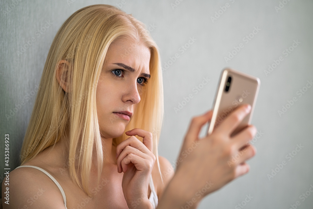 The frowning woman looks at the phone. The frowning woman looks at the phone.