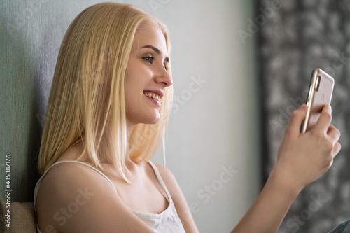 Beautiful young blonde woman holding a phone in her hands and smiling.