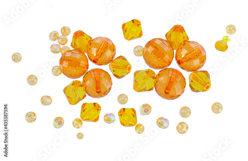 A layout of orange and yellow beads of different shapes isolated on a white background.