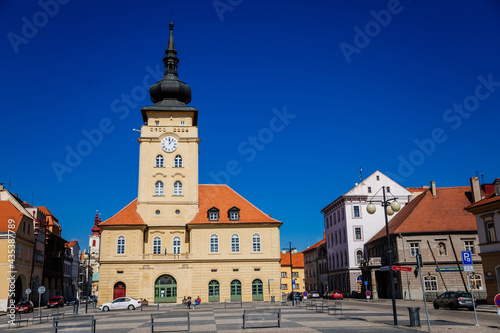 Yellow classic town hall with clock tower at main Freedom square, renaissance and baroque historical buildings, blue sky, Medieval street, sunny day, Zatec, Bohemia, Czech Republic