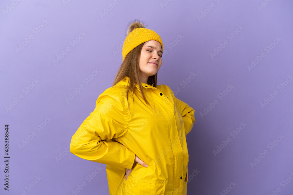 Teenager girl wearing a rainproof coat over isolated purple background suffering from backache for having made an effort Teenager girl wearing a rainproof coat over isolated purple background suffering from backache for having made an effort