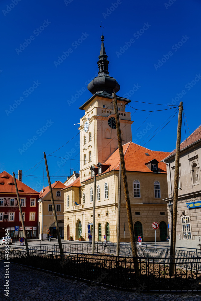Medieval Yellow classic town hall with clock tower at main Freedom square, renaissance and baroque historical buildings, small hop garden, sunny day, Zatec, Bohemia, Czech Republic