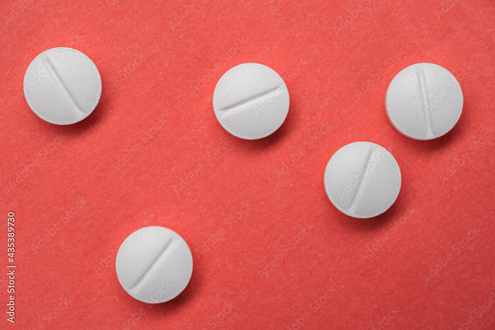 White pills on a red background. White pills on a red background.