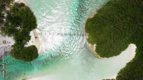 Aerial Spinning Away From An Abandoned Boardwalk Connecting Two Small Tropical Islands With Lush Green Plants, Bright Sand, And Sunlight Reflecting Off The Rippling Water - Thulusdhoo, Maldives photo