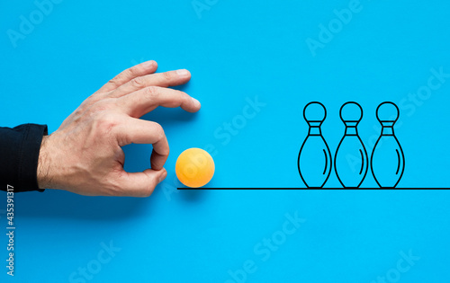 Male hand is about to flick the ball and knock or strike the bowling pins