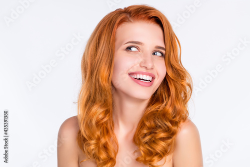 Photo portrait of pretty girl with wavy ginger hair smiling with naked shoulders looking empty space isolated on white color background