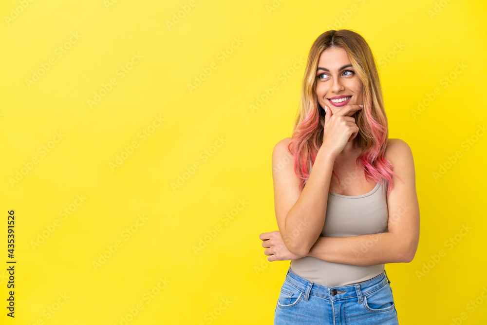 Young woman over isolated yellow background looking to the side and smiling