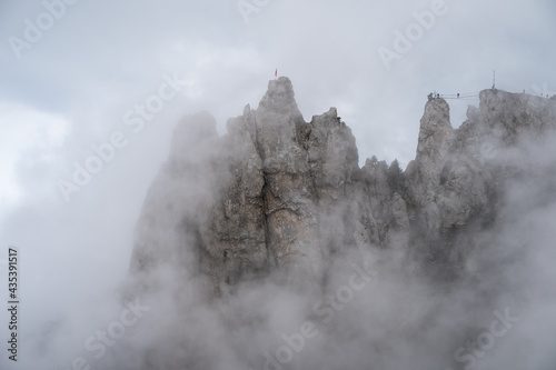 Rocks in dense fog and clouds. Dramatic gloomy mountain landscape.