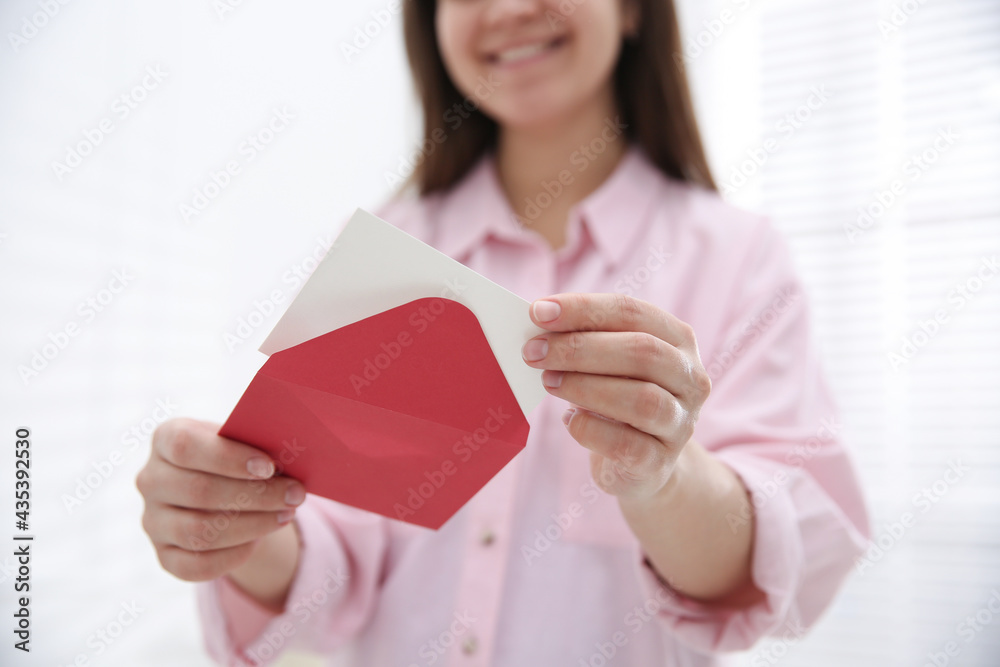 Woman holding envelope with blank greeting card at home, closeup Woman holding envelope with blank greeting card at home, closeup