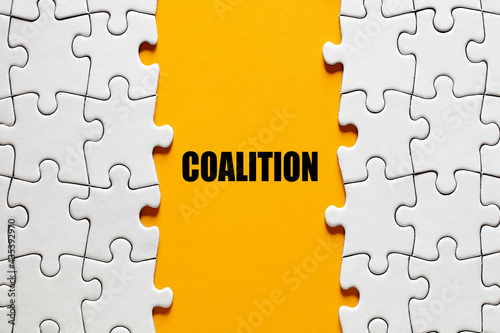 The word coalition between the jigsaw puzzle pieces. Alliance, cooperation and collaboration in business or politics photo