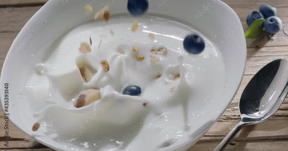 Cereal breakfast (granola) with fresh blueberries slowly fall into the yogurt on a plate in the morning light. 300fps Cereal breakfast (granola) with fresh blueberries slowly fall into the yogurt on a plate in the morning light. 300fps