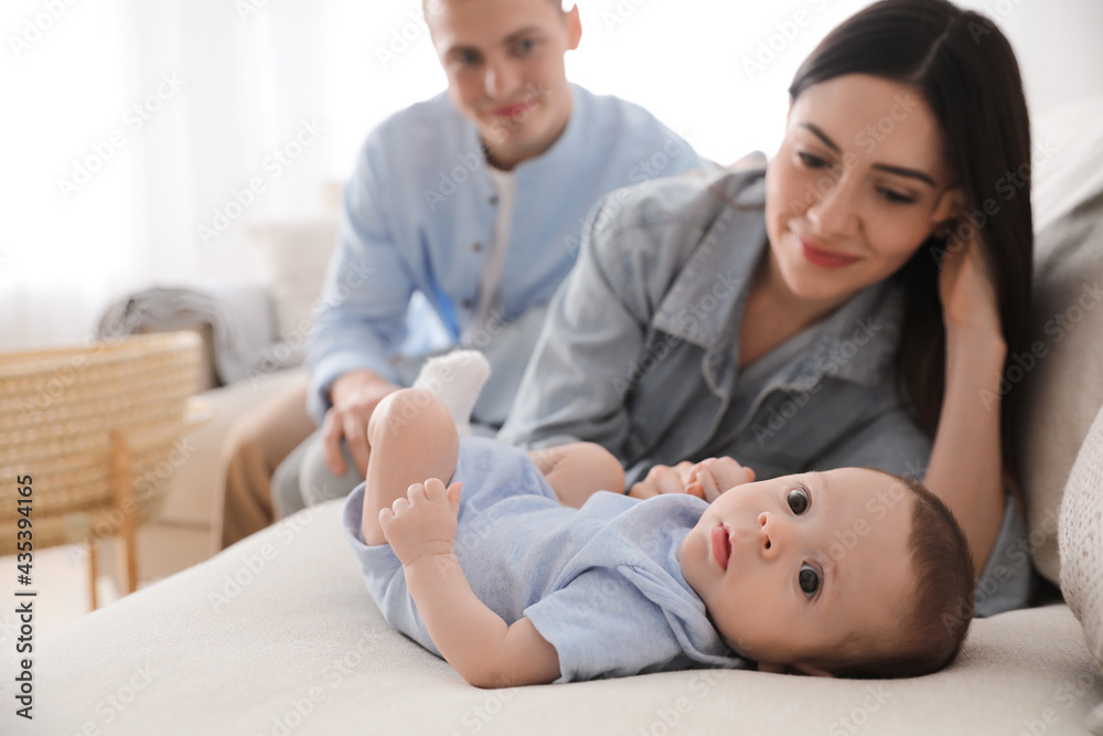 Happy family with cute baby on sofa at home, space for text