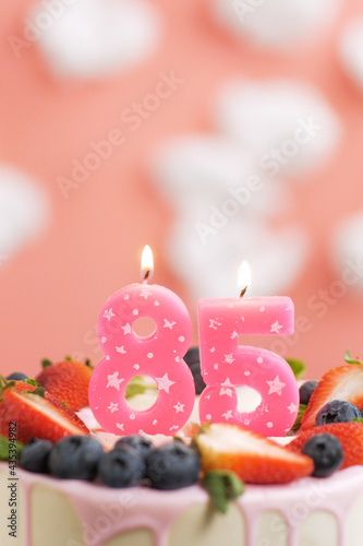 Birthday cake number 85. Beautiful pink candle in cake on pink background with white clouds. Close-up and vertical view © Stanislav